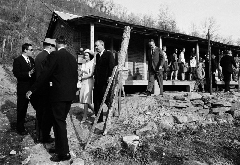 President Lyndon Johnson and his wife, Lady Bird, center left, leave the home in Inez, Ky., of Tom Fletcher, a father of eight who told Johnson he'd been out of work for nearly two years, in this April 24, 1964, file photo. The president visited the Appalachian area in Eastern Kentucky to see conditions firsthand and announce his War on Poverty from the Fletcher porch.