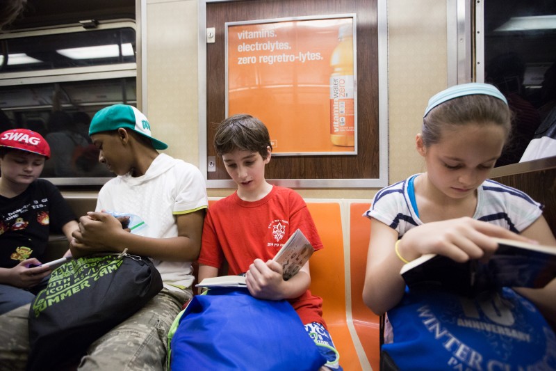 Student Etai Kurtzman, 12, reads a book on the train to Coney Island in Brooklyn, NY May 28, 2015. The group of students from Quest to Learn School took the day trip to Coney Island to analyze user experience on games and rides at Luna Park as part of their late-spring school curriculum.
