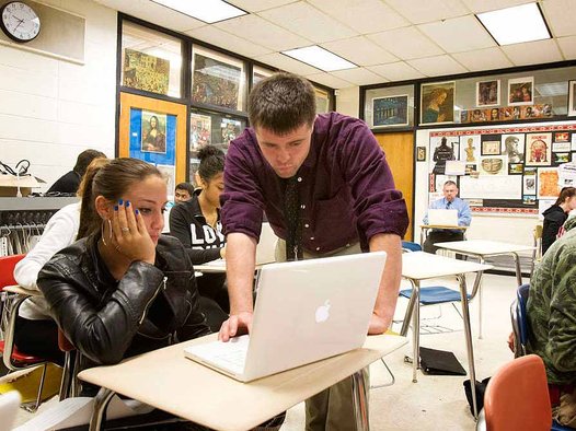 At Upper Darby High School, first-year teacher Joe Niagara works with senior Amanda Farina in class while Principal Christopher Dormer (seated, rear) observes and takes notes for Niagara's evaluation. (Photo courtesy Philadelphia Inquirer)