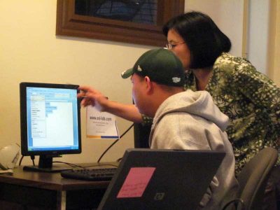 Mya Maw, 52, helps other students in Boston’s Hotel Training Center’s lowest level computer skills class. Maw, a hotel dishwasher, takes the next level computer course and English classes at the center. (Photo by Sarah Butrymowicz)