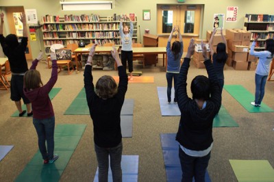 Mary Kay Bisignano-Vadino, background facing camera, leads incoming ninth graders participating in a "street yoga" class during the Summer Bridge program at West Seattle High School. (Ken Lambert/The Seattle Times)