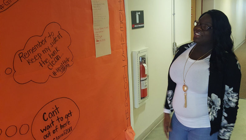 Rutgers Newark sophomore Stacy Tyndall, 19, laughs at an "Orange Is the New Black"-themed wall of dormitory rules in her campus residence hall. Tyndall, a criminal justice major who wants to be a judge, grew up 15 minutes from the campus.
