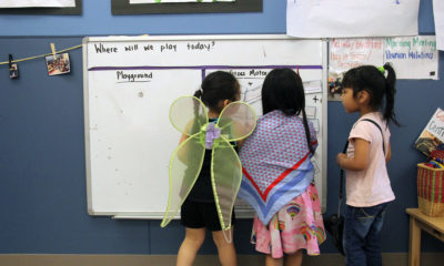 Students play dress-up and draw on a whiteboard in a Christopher House preschool class.
